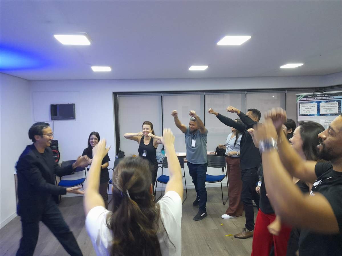 Turma do Seminário de Inteligência Emocional com PNL em São Paulo em dinâmica com os braços erguidos, conduzida por Claudio Shen